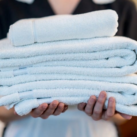 Housekeeper Holding Stack of Towels