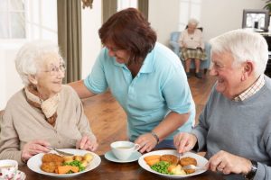 Senior Couple Eating and Speaking with a Care Professional